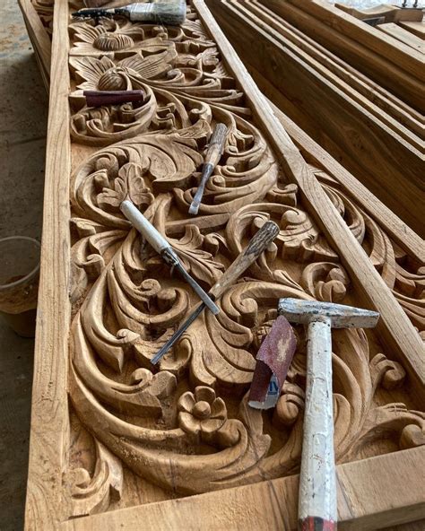 An Intricately Carved Wooden Panel With Tools Laying On The Floor Next