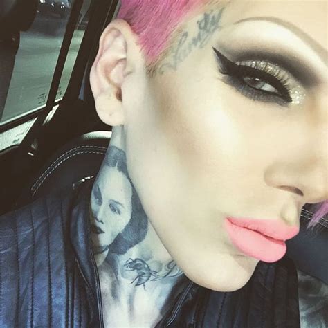 A Woman With Pink Hair And Tattoos On Her Face Is Sitting In A Car