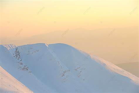 غروب الشمس فوق التلال مع جبال الثلج في منظر طبيعي للثلوج مع غروب الشمس فوق التلال الخلفية بيئة