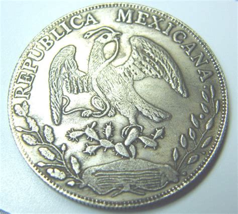 an old mexican silver coin with the eagle on it's reverse side, sitting ...