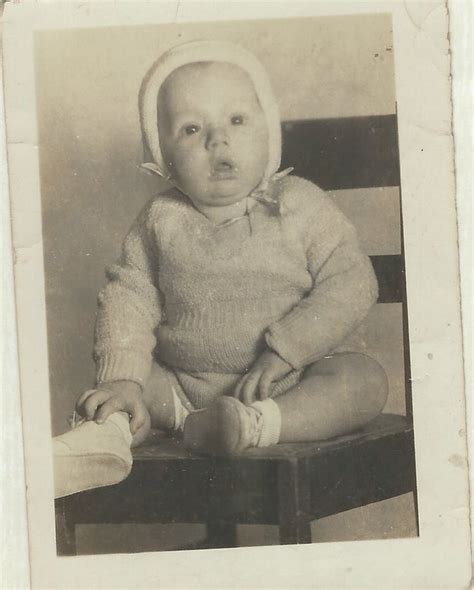 An Old Black And White Photo Of A Baby Sitting On A Chair