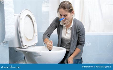 Portrait Of Young Brunette Woman Washing Dirty Stained Toilet Stock