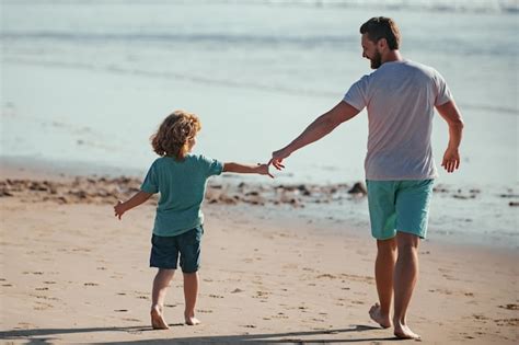 Pai e filho andando no mar pai e filho de mãos dadas e caminham juntos