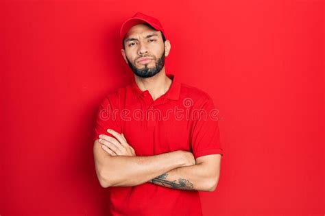 Hispanic Man With Beard Wearing Delivery Uniform And Cap Skeptic And