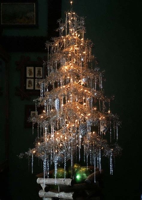 A Small Christmas Tree Is Lit Up With Lights And Icicles In The Shape