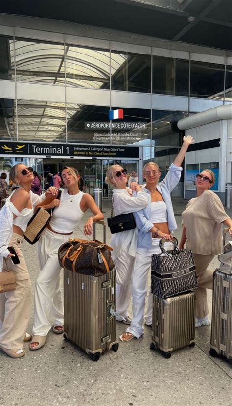 Four Women Are Standing With Their Luggage At The Airport And Waving To