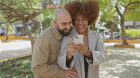 Interracial Couple Laughing And Taking A Selfie In A Sunny Urban Park