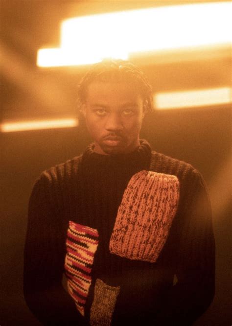 A Man With Dreadlocks Standing In Front Of A Yellow And Red Light