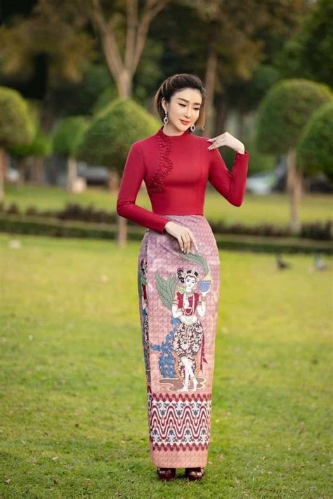 A Woman Standing In The Grass Wearing A Red Top And Patterned Skirt