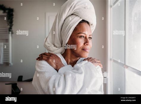 Mature Woman Wearing Bathrobe Looking Through Bathroom Window Stock