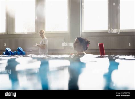 Smiling Woman With Noodle Float In Swimming Pool At Rehabilitation