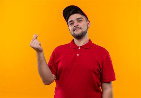 Repartidor Joven En Uniforme Rojo Y Gorra Frotando Los Dedos Haciendo