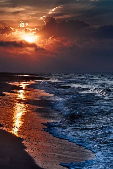 The Sun Is Setting Over The Ocean With Clouds In The Sky And Waves On