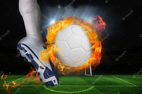 Premium Photo | Football player kicking flaming ball against football ...