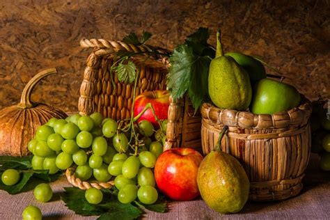 A Basket Filled With Lots Of Different Types Of Fruit Next To Green