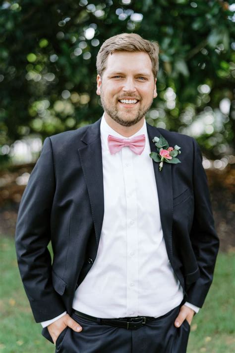 Groom Wears Pink Bow Tie And Black Suit Pink Boutonniere Wedding