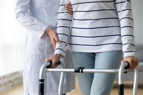 Female Nurse Helping Old Grandmother Patient Using Walking Frame