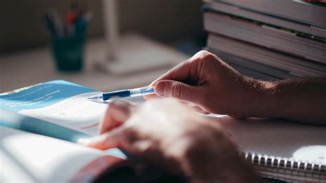 person holding blue ballpoint  writing  notebook  stock photo