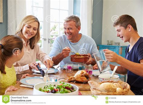 Familia Que Disfruta De La Comida En Casa Junto Imagen De Archivo