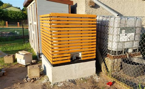 A Wooden Box Sitting On The Side Of A Building Next To A Fenced In Area