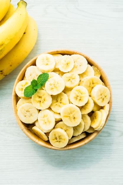 Fatias de banana amarela crua na tigela de madeira Foto Grátis