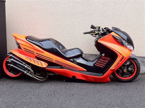 An Orange And Black Motorcycle Parked Next To A Building