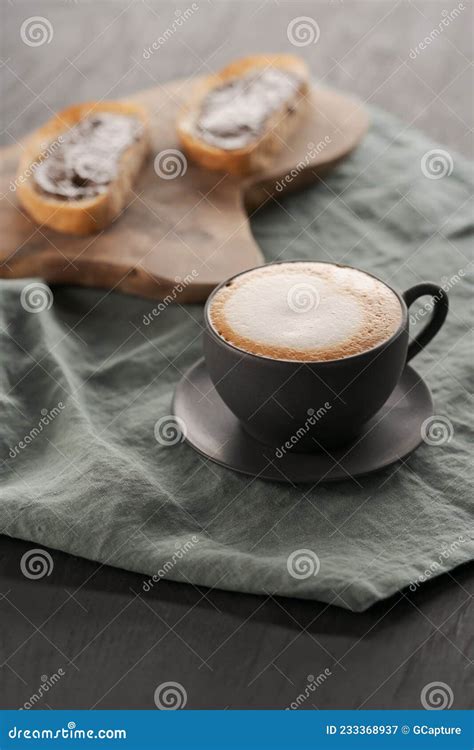 Cappuccino In Black Cup With Ciabatta Slices With Chocolate Spread On