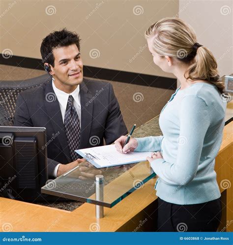 Receptionist Greeting Man At Front Desk Royalty-Free Stock Photography