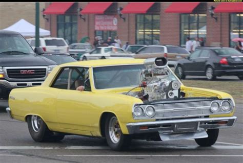 A Yellow Car Driving Down A Street Next To Other Cars