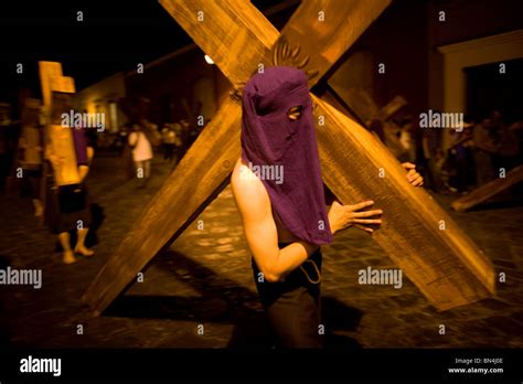 A Hooded Penitent Carries A Cross During Holy Week Celebrations In