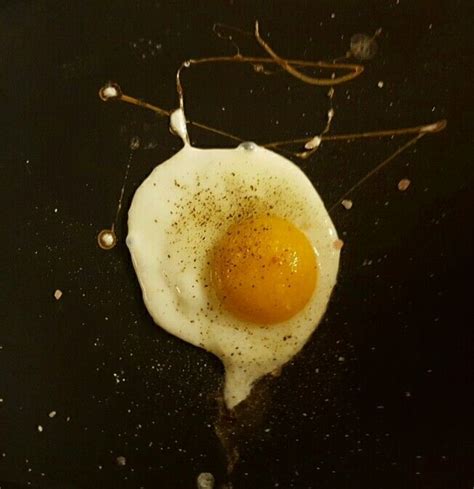 An Egg Frying In A Skillet On Top Of A Black Surface With Brown Sprinkles