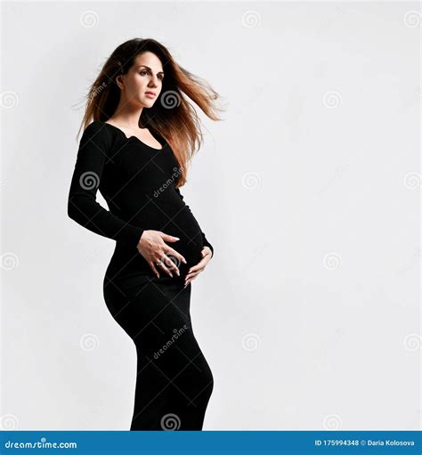 Brunette Pregnant Woman In Black Tight Dress She Put Hand On Her Belly While Posing Sideways