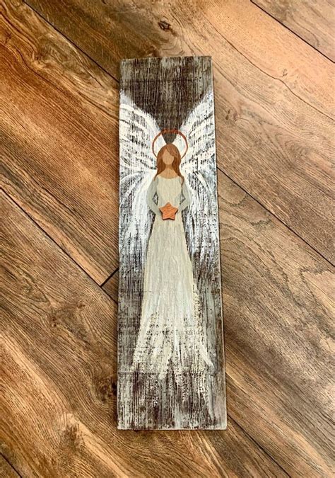 An Angel Painted On Top Of A Wooden Plaque