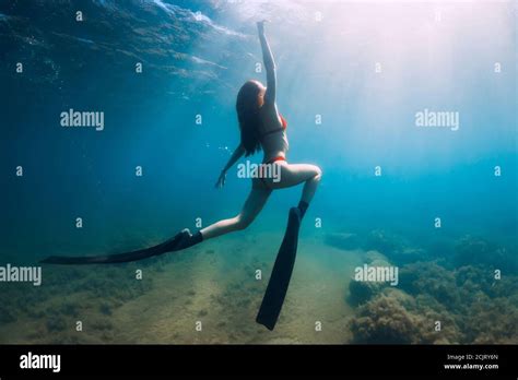 Freediver Slim Woman In Bikini Glides In Blue Sea And Sun Rays