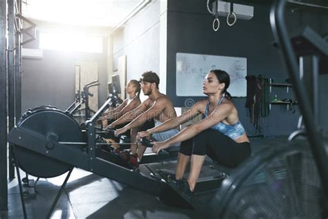 Crossfit. People Exercising on Rowing Machine in Training Gym Stock ...