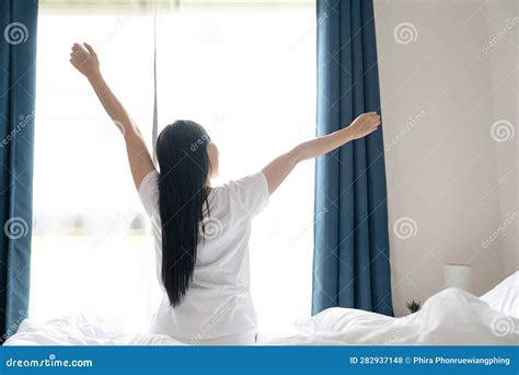 Young Asian Woman Sitting On The Bed And Stretch Oneself In The Morning