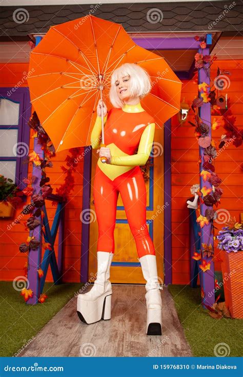 Une Jolie Femme Blonde Chaude Dans Un Costume En Latex Brillant Et Coloré Prêt Pour La Fête D