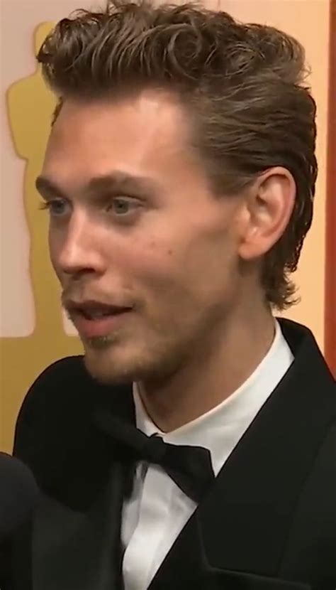 A Man In A Tuxedo And Bow Tie Talking To Someone At An Event