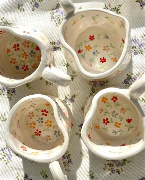 Four Flowered Cups And Spoons On A Tablecloth