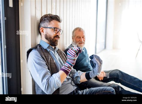 Portrait Of Adult Hipster Son And Senior Father Sitting On Floor