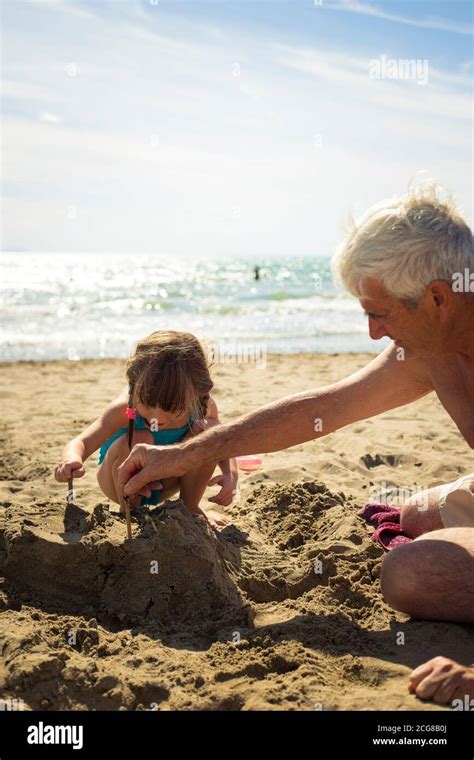 Grand père et petite fille caucasiens jouant avec du sable