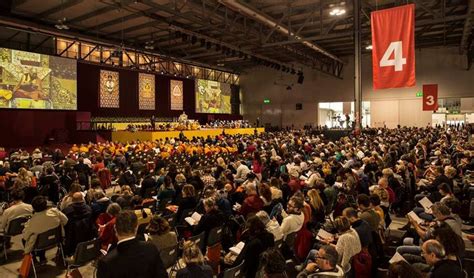 A Large Group Of People Are Sitting In A Hall With Red And Yellow