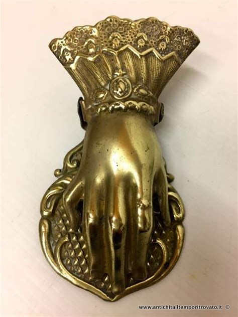 A Gold Colored Metal Object On A White Surface With An Ornate Hand