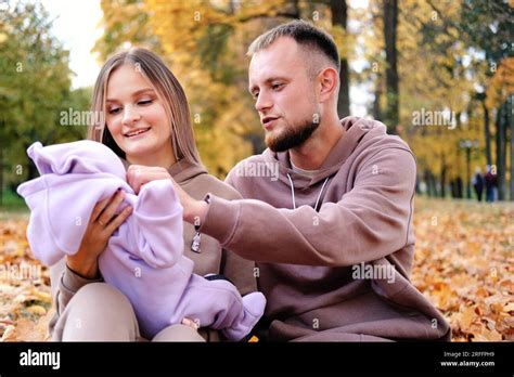 Los padres jóvenes se sientan en una cuadros con un bebé recién nacido