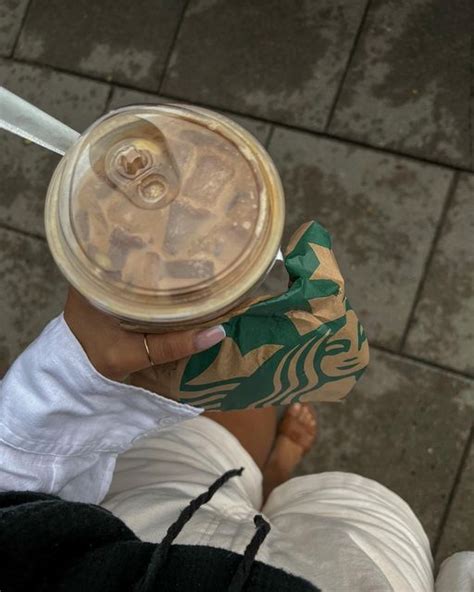 A Person Holding A Starbucks Drink In Their Hand