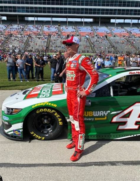 a man standing next to a green and white car in front of a large crowd