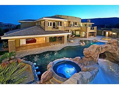 a large house with a pool in the middle of it and some rocks on the ground