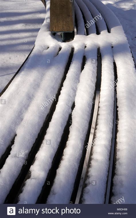 Snow accumulation on slatted wood bench Stock Photo - Alamy