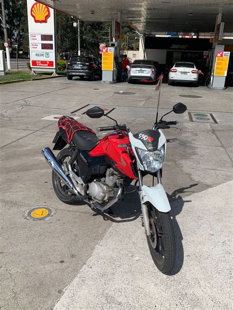 A Red And White Motorcycle Parked In Front Of A Gas Station