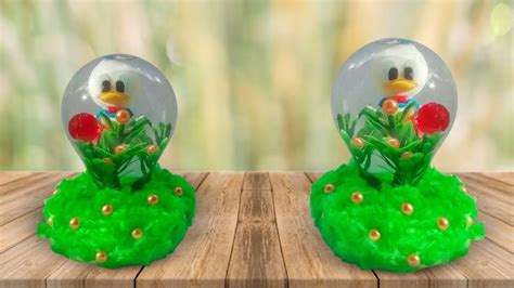 Two Snow Globes Sitting On Top Of A Wooden Table Covered In Grass And